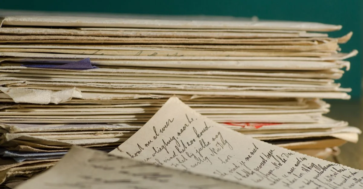 Image en gros plan de lettres manuscrites et de papiers empilés, transmettant une ambiance vintage.