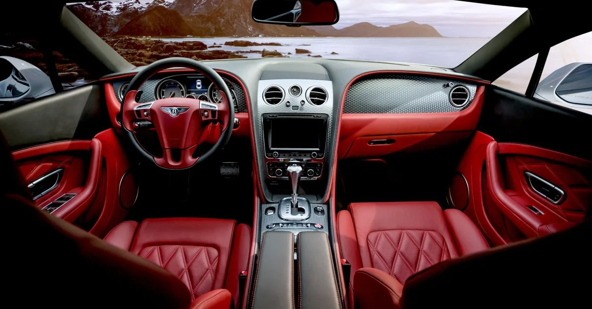 Intérieur en cuir rouge d'une voiture de sport de luxe avec un décor montagneux visible par la fenêtre.