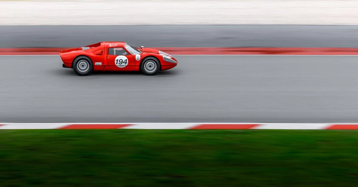 Voiture de course rouge vintage roulant à toute vitesse sur une piste avec un flou de mouvement pour un effet dramatique.